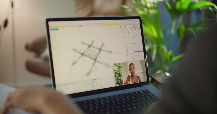 Graphic designer uses a laptop to view a blueprint for a drone while on a video call