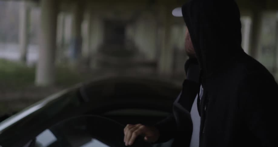 A man gets out of a car parked under an overpass