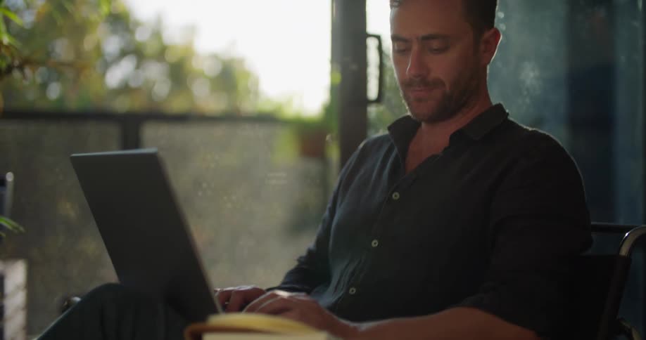 Man sitting on a chair at home working on a laptop at morning
