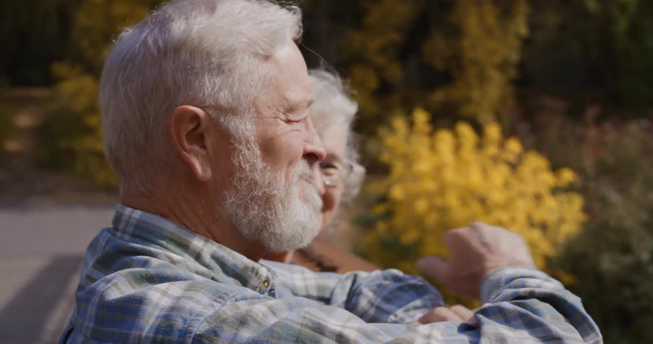 Elderly couple leisurely sitting on a bench in a park at morning