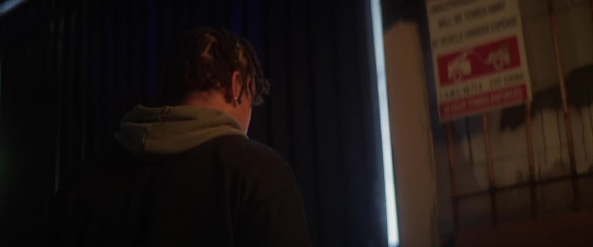 Young man walks towards a door opening into a brightly lighted room