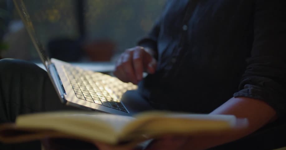 Man sitting on a chair at home working on a laptop talking on a video call at morning