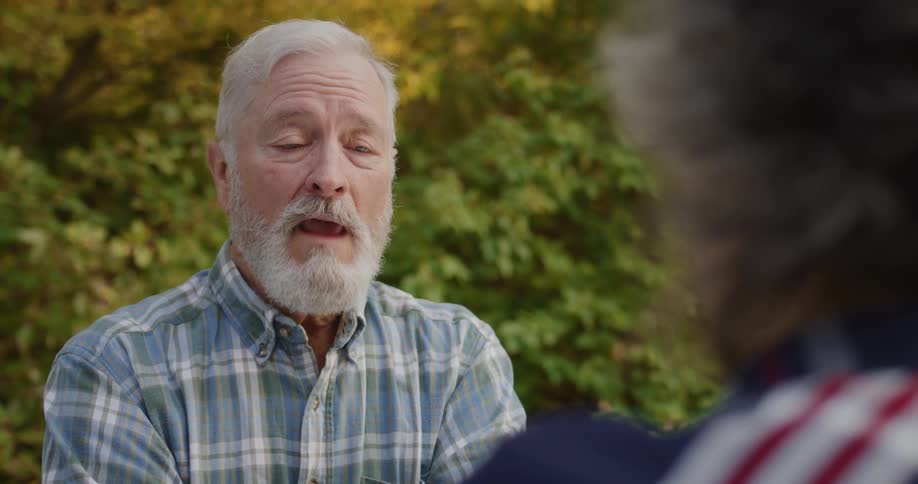 An elderly man in a forest talks to a woman