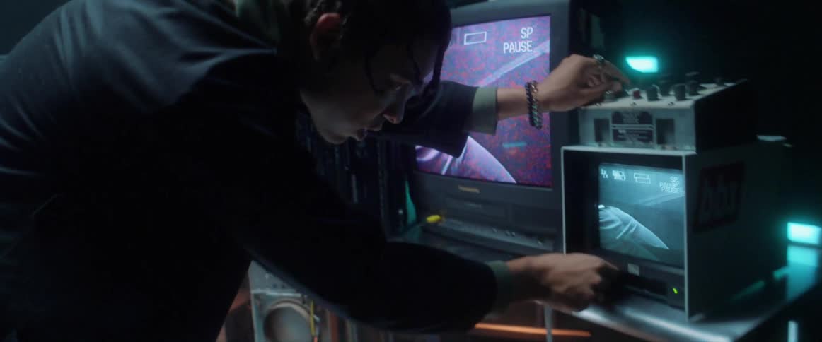 Young man manipulates electronic equipment inside a dimly lit room