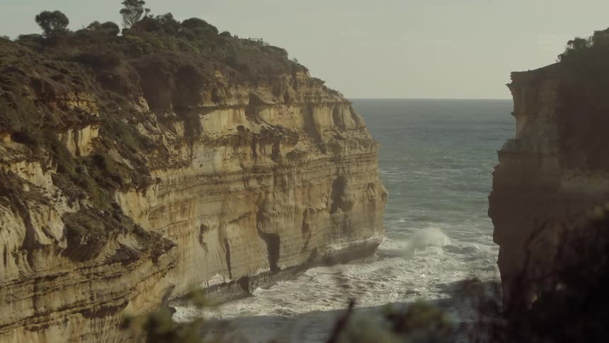 Waves crash and roll in the gap between two tall cliffs