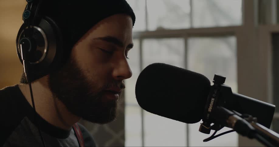 Young man wearing headphones singing into a microphone at home