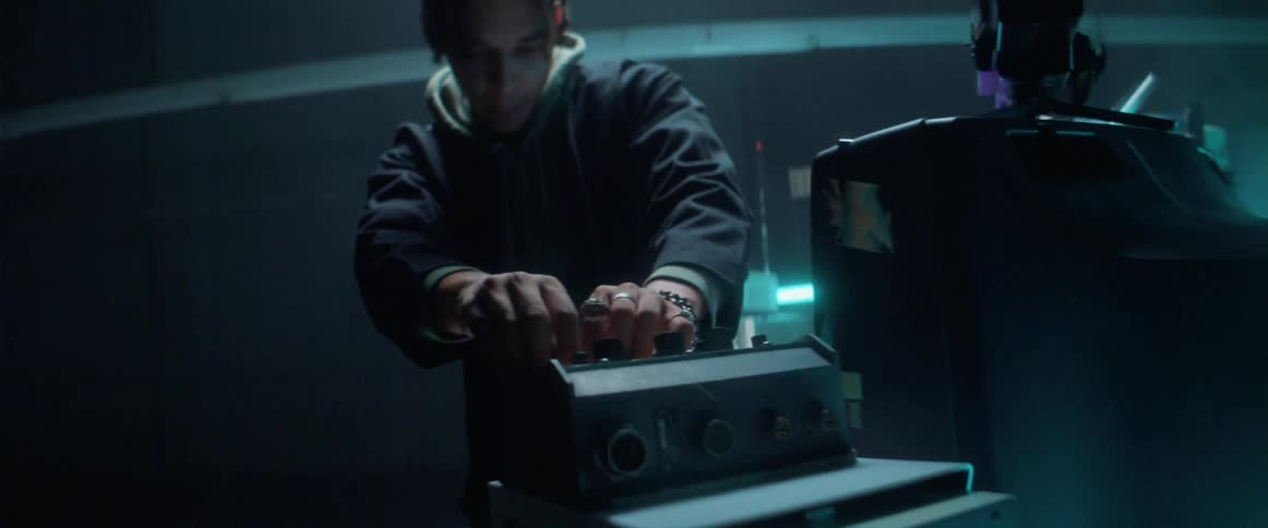Young man manipulates electronic equipment inside a dimly lit room