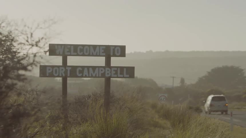 A sign is by the side of the road on a foggy day