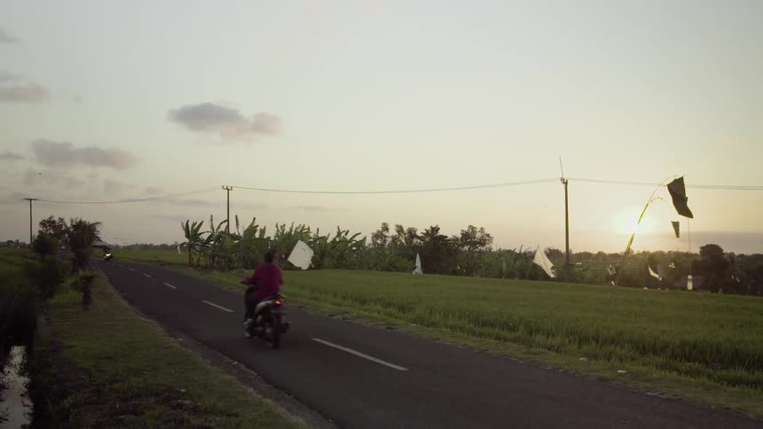 Motorcyclists driving along a two lane road on a windy day