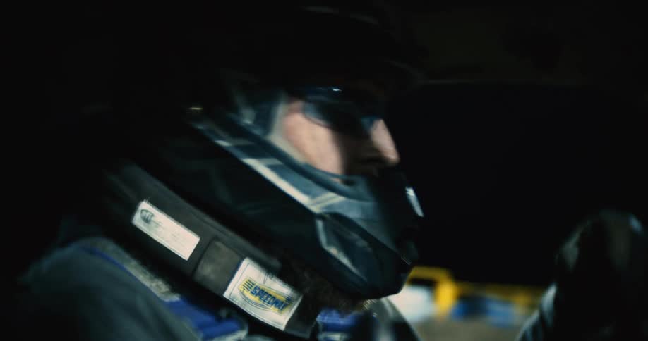 A driver looks back as his car bumps along the dirt stadium in a demolition derby