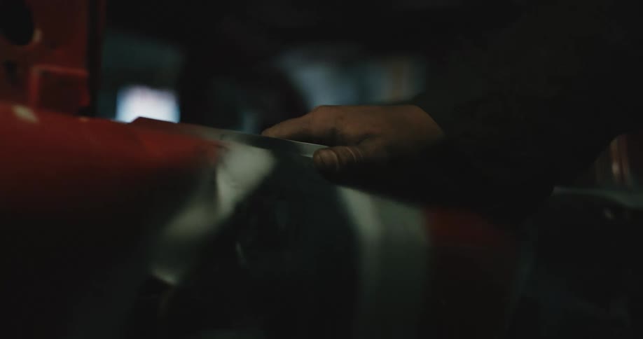 A mechanics hand rests on a painted car frame