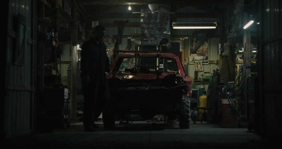 A man smokes as he walks around his race car and looks at it