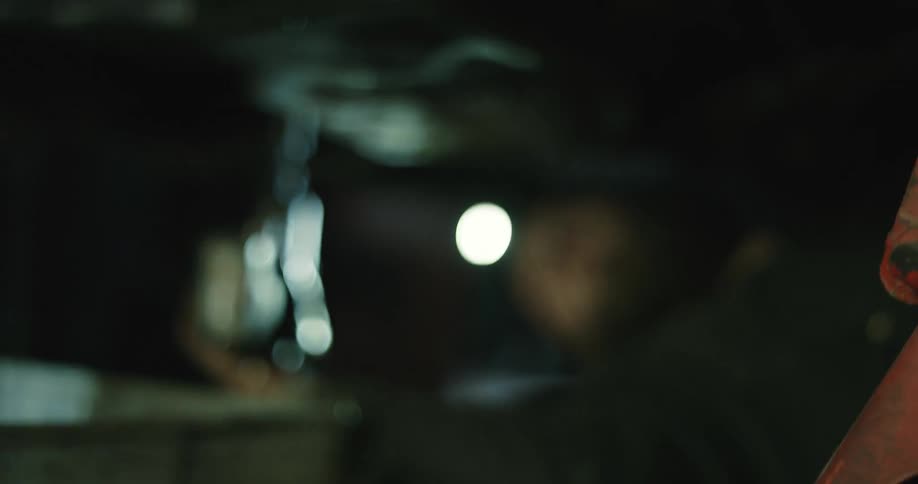 A mechanic wears a head lamp while drilling under a vehicle