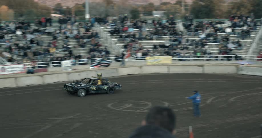 A car is racing in the middle of the day with people in the crowd