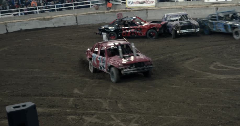 Cars are racing outside in front of a crowd of people