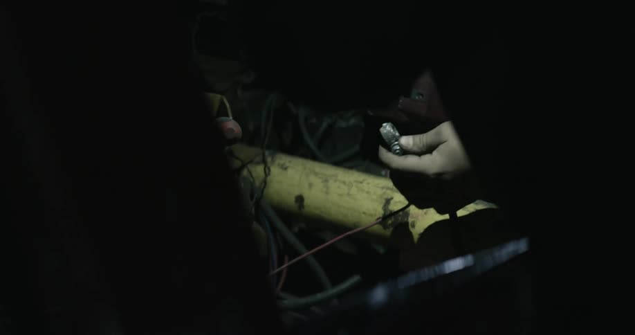 An electrician works on wires in a dark room