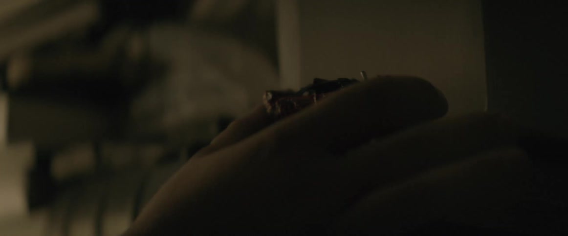 A hand reaches and picks up a small metallic object