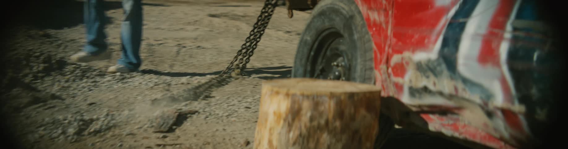 Men are near an old junker race car pulling a chain to the front