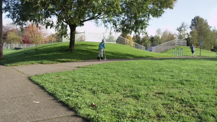 Children ride scooters in a park