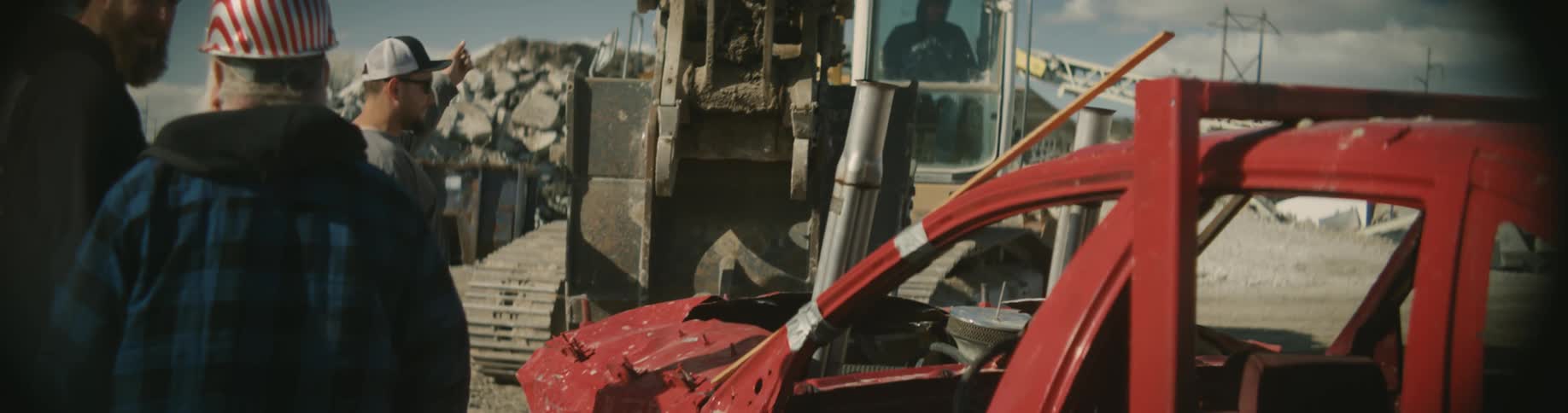 An excavator is being used to lift a wrecked vehicle