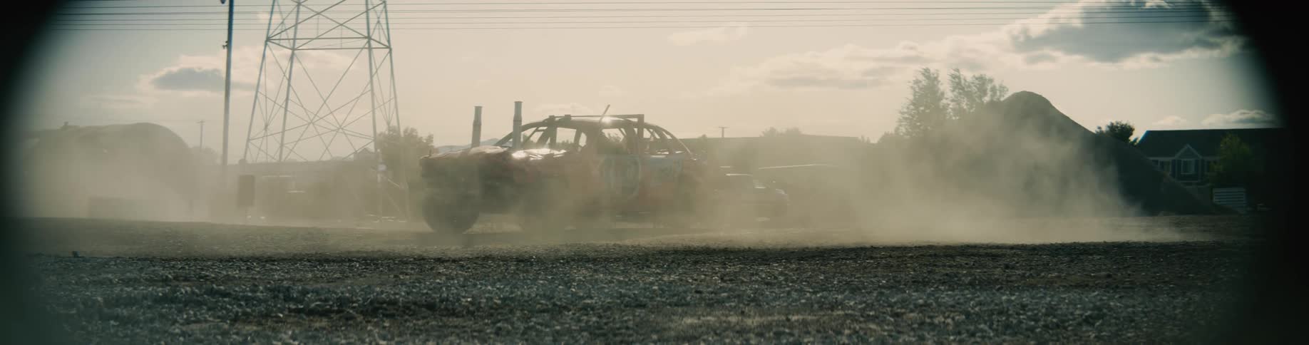 A vehicle is leaving a dust cloud as it travels