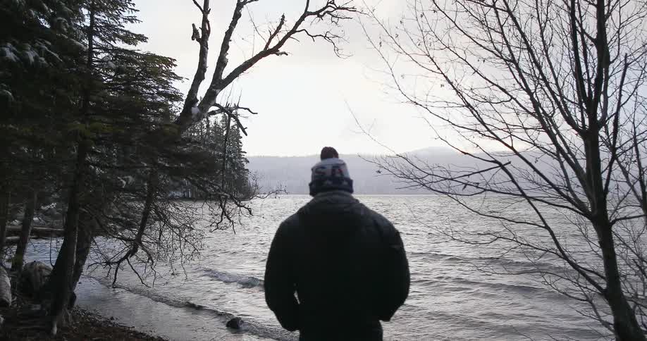 A man walks past a camp towards the water