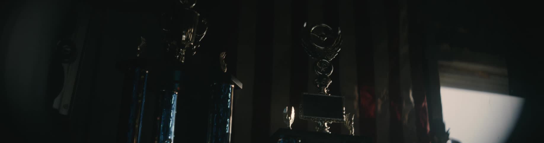 Shiny metal pipes with valves are positioned vertically in a dark room