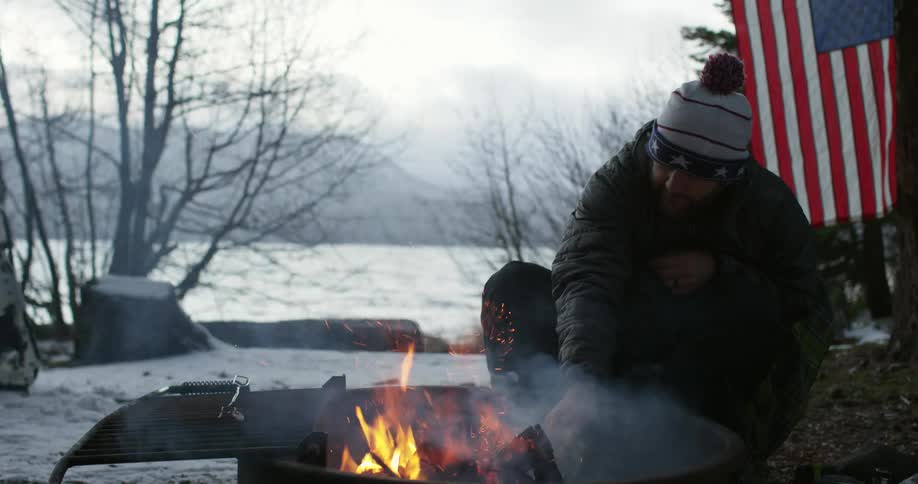 A man is moving some sticks around in a campfire