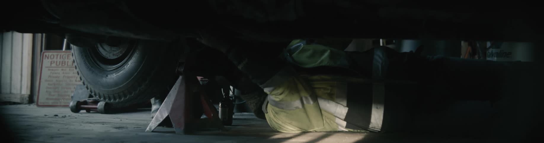 A mechanic lying on his back underneath a jacked up car making repairs