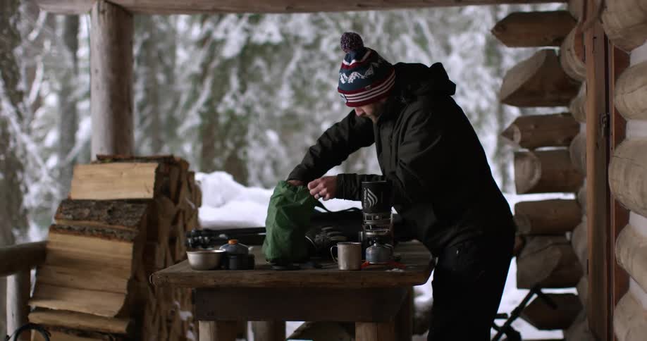 A man is standing on a porch before removing items from a bag