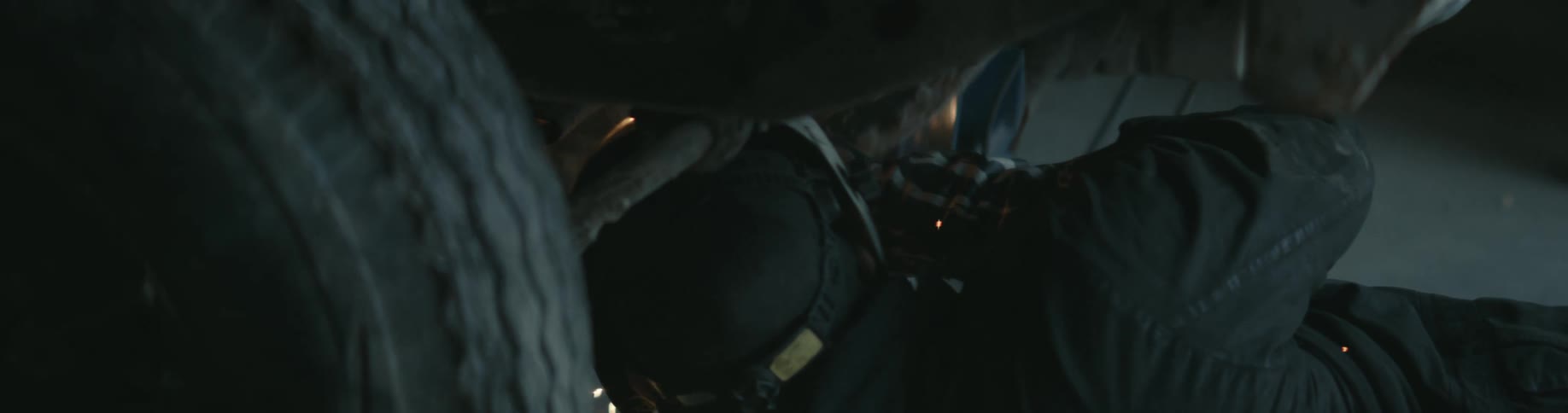 A mechanic is welding under a vehicle