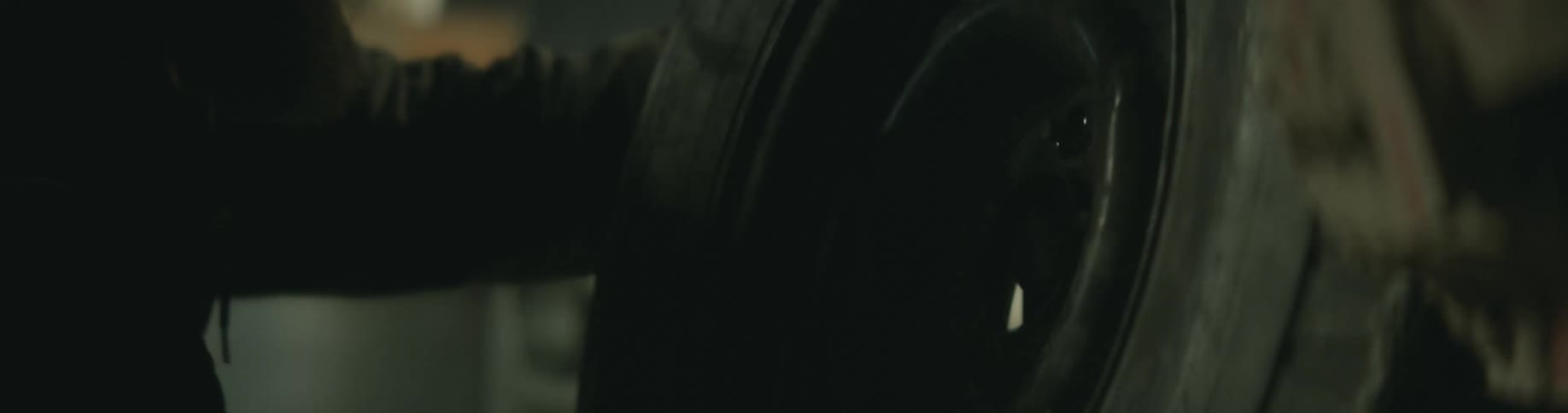 A man is working on a car and holding a tire