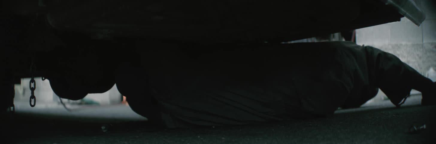 A mechanic is under an automobile working on it