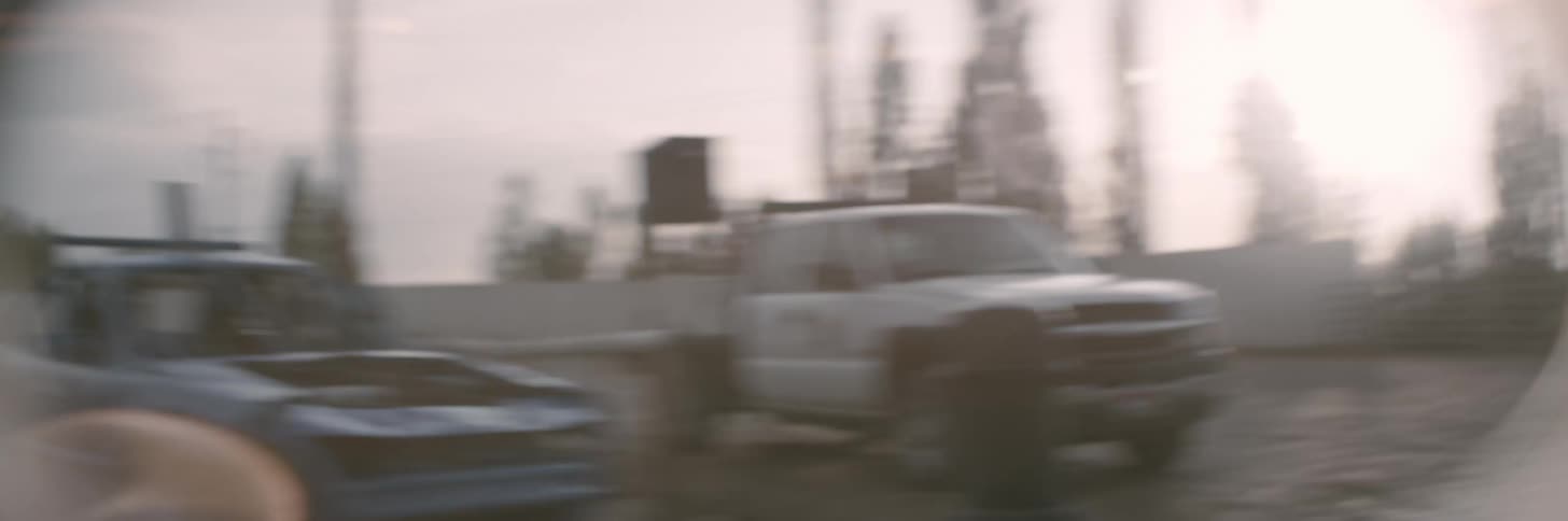 Demolition derby cars make their way into a stadium with drivers and passengers waving