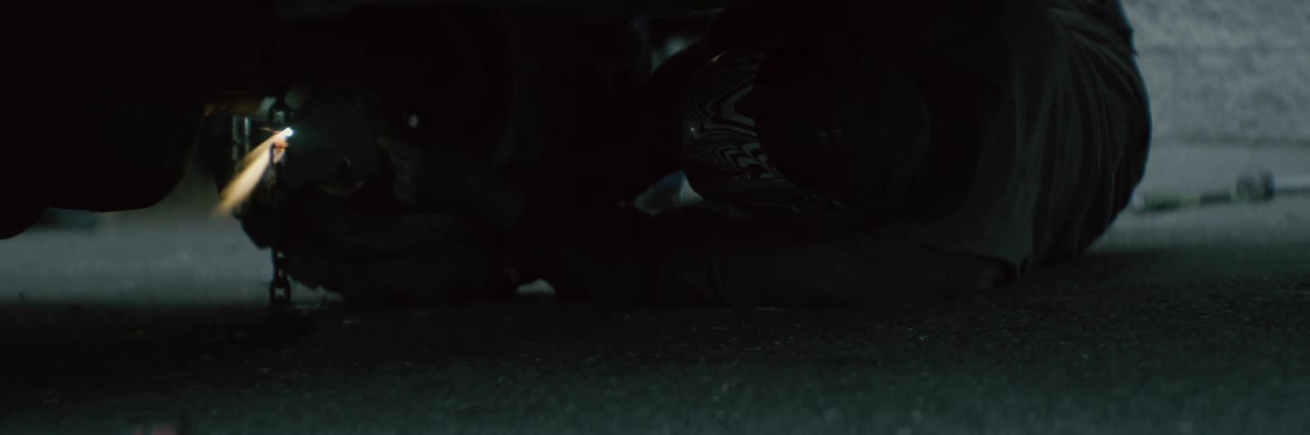 A person is on the ground fixing a car with there tools