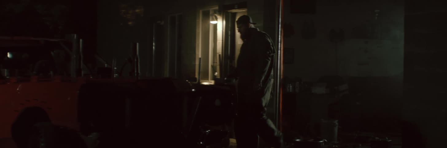 A man is walking outside of a house near a parked car