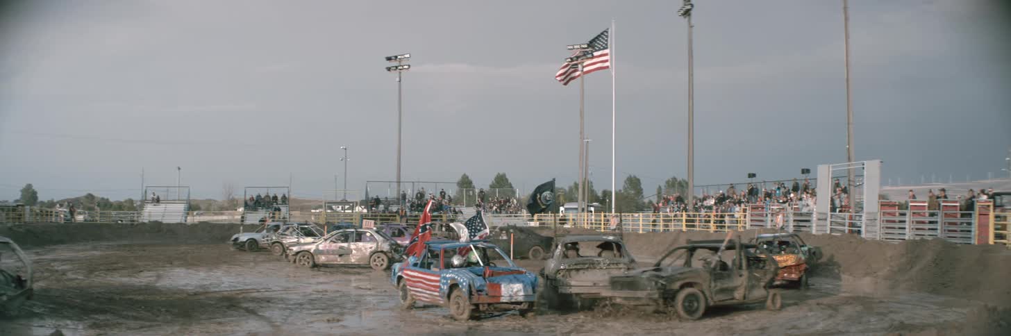 Cars sliding around on a muddy track and crashing into each other during a demolition derby