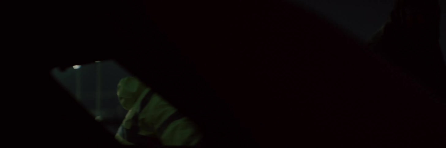 A man walks around a car at night