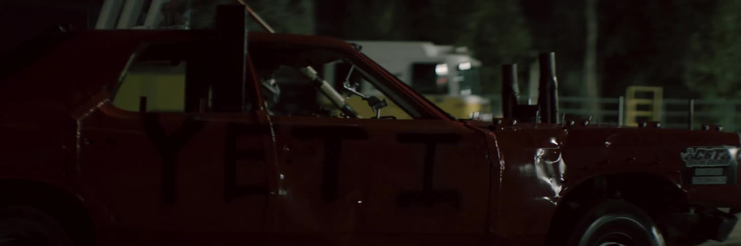 Vehicles driving outside in the night time while people are walking by