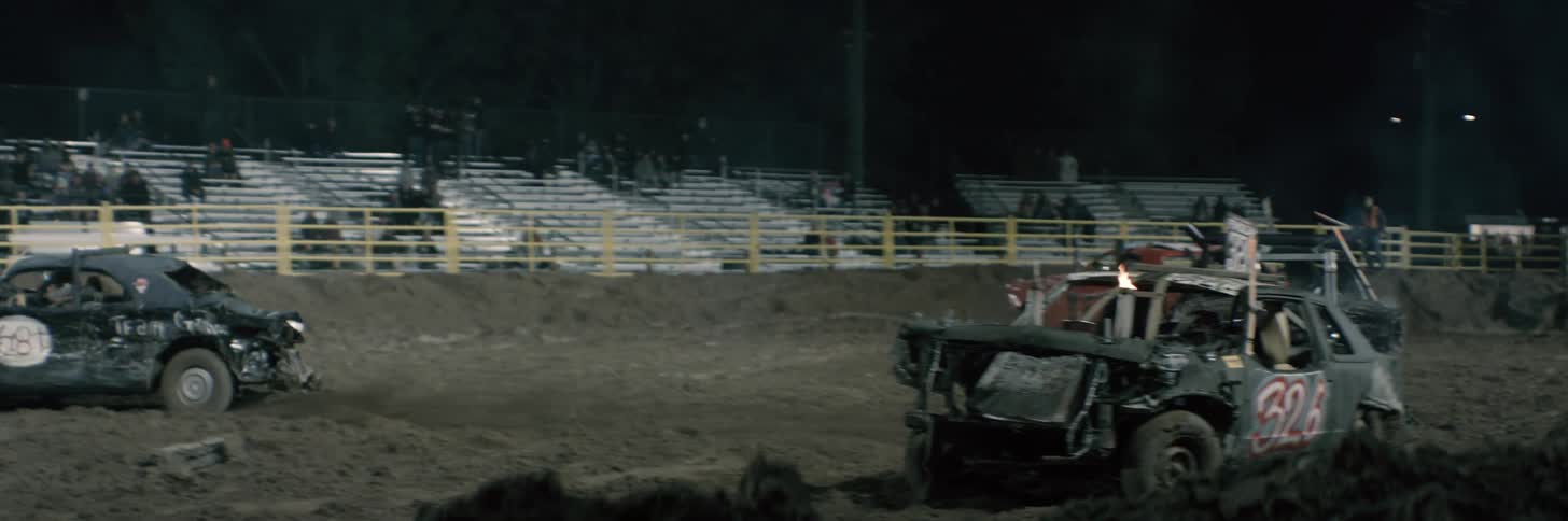 Smashed cars are crashing into each other in a demolition derby and flames are coming from one car