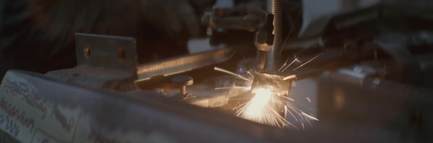 A mechanic using a blowtorch to weld metal causing sparks to fly