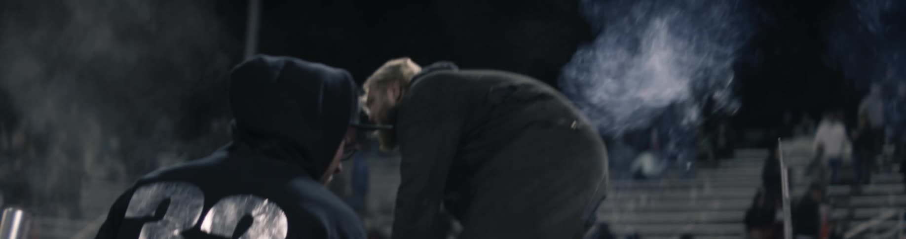 A man jumps out of a wrecked car in an arena as an audience watches