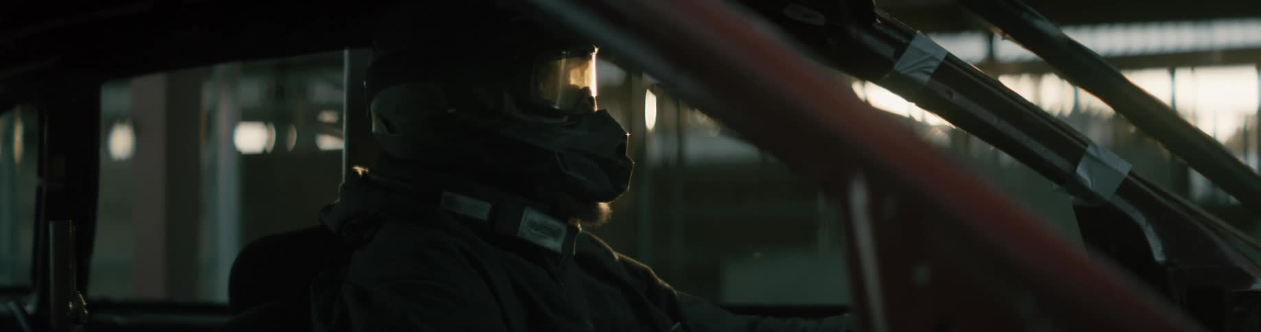 A man wearing a helmet sits in a car and waits
