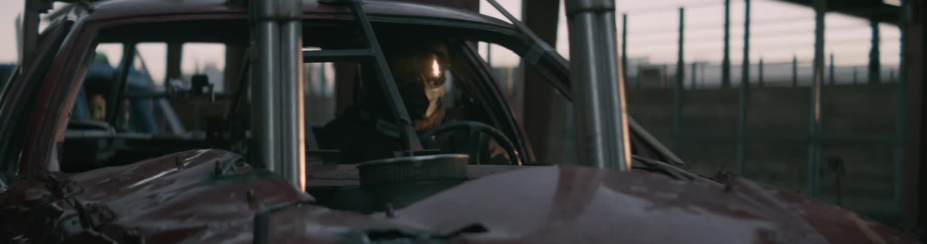 A man with a mask and helmet is sitting in a racecar in a line of cars