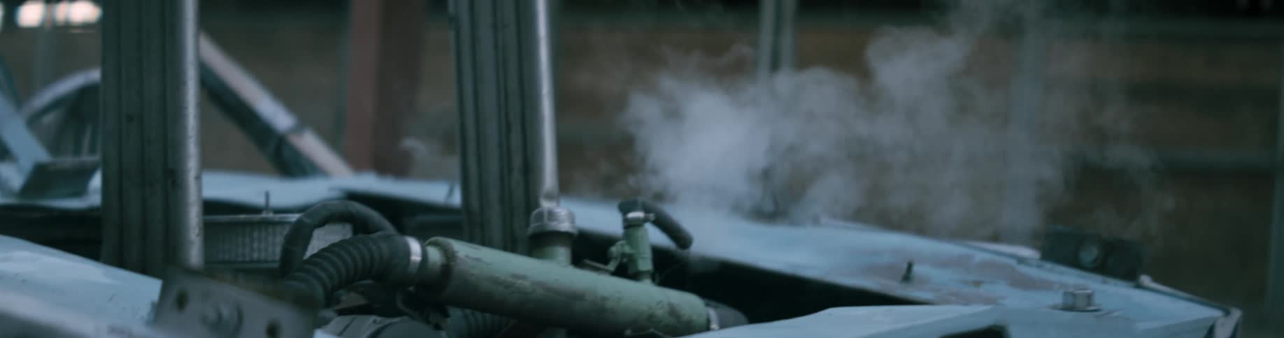 A race car is parked with the engine smoking inside a building