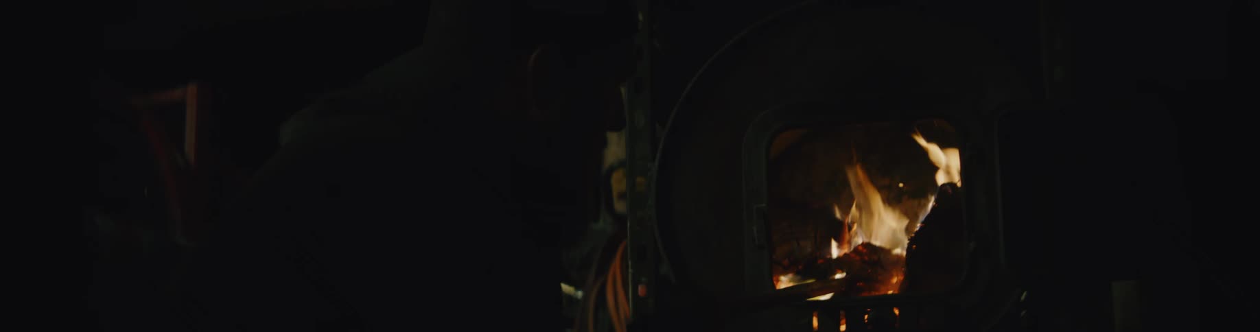 A person is using a stick to stoke a log fire on a dark night