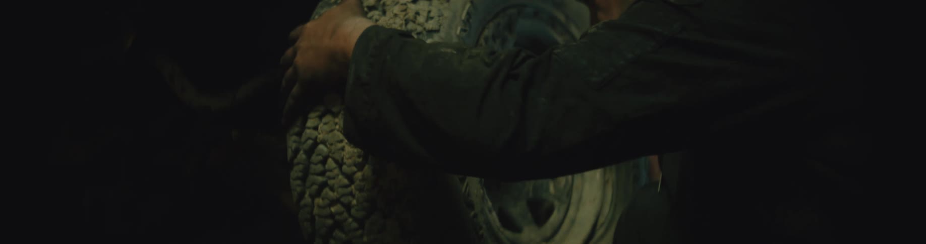 A man lifts a tire up and places it on a vehicle
