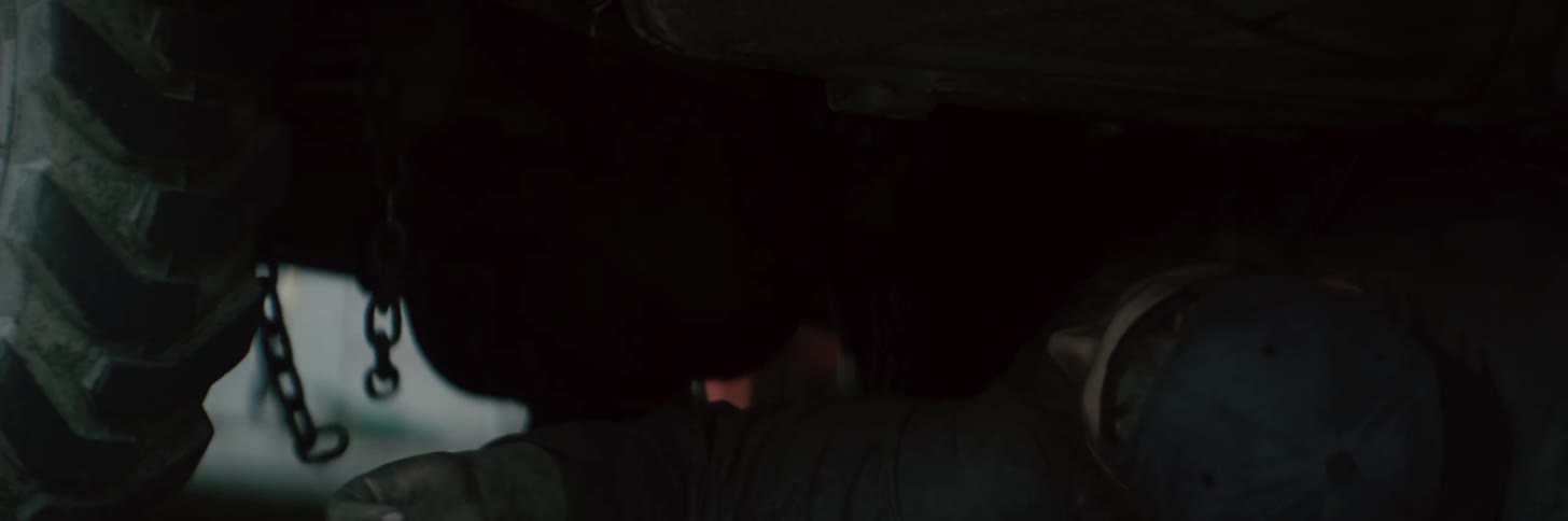 A man is under a car that has a chain hanging down