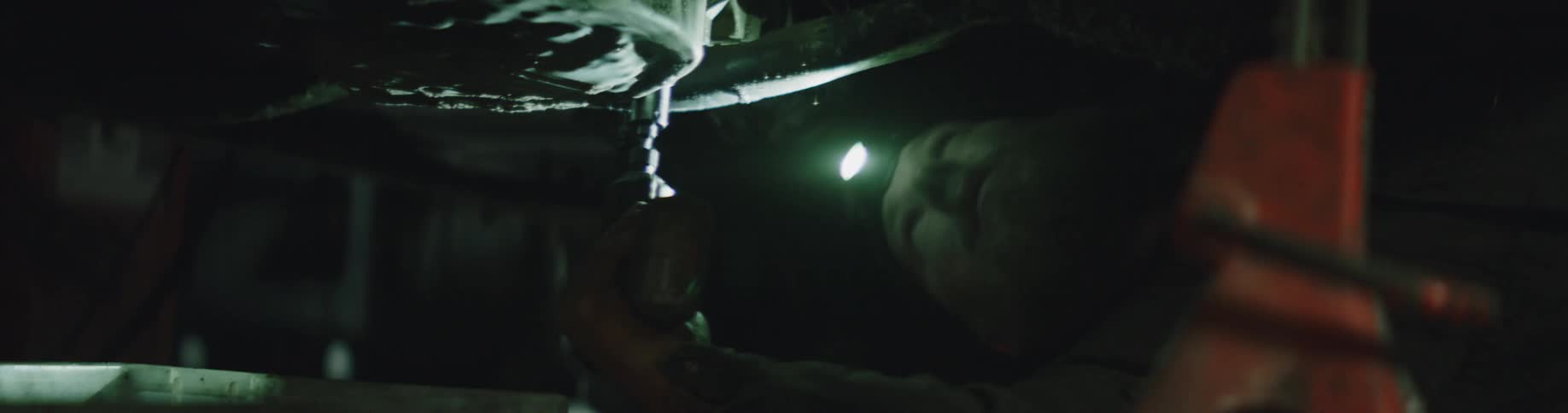 A mechanic is working under the vehicle