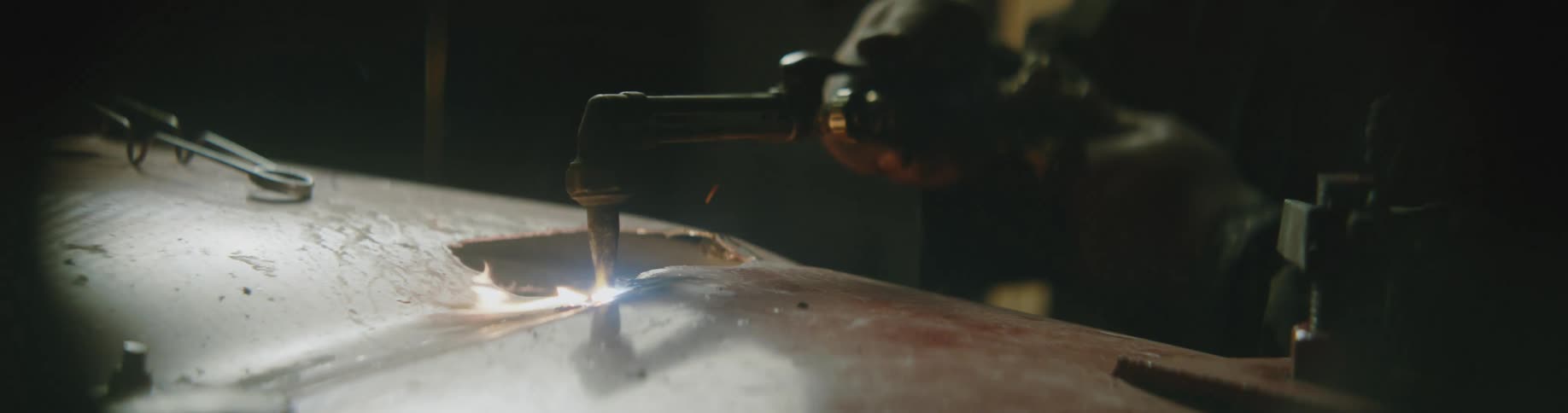 A man is using a welding torch on a hole of a car